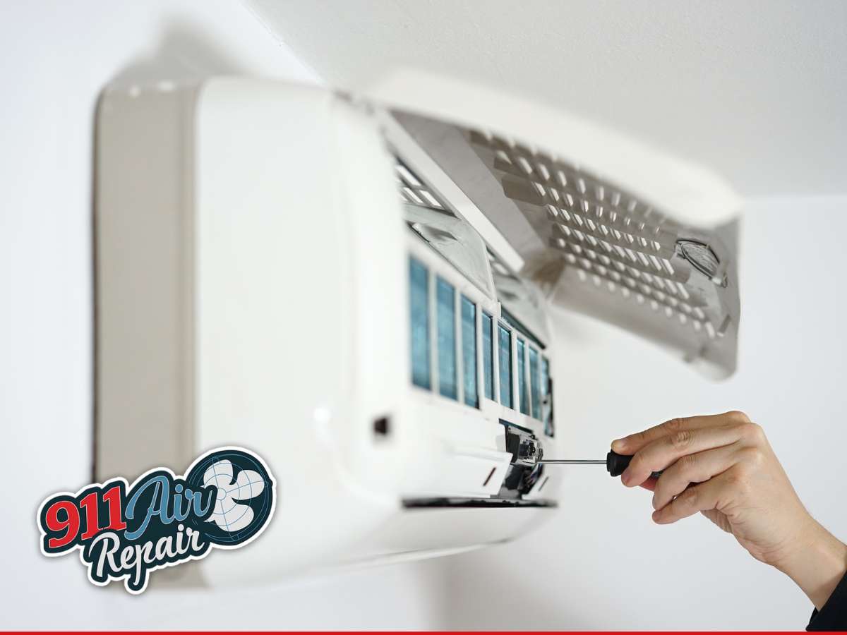Technician performing AC Maintenance on a wall-mounted unit - 911 Air Repair logo visible
